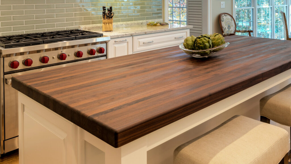 Custom walnut hardwood island countertop with off-white cabinetry in a kitchen