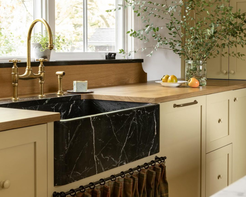 White oak kitchen countertops paired with a black stone farmhouse sink and painted cabinetry