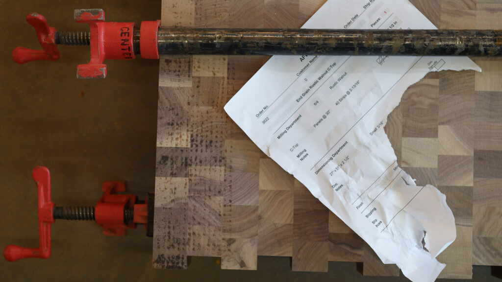 End-grain walnut countertop fabrication with project paperwork and clamp assembly