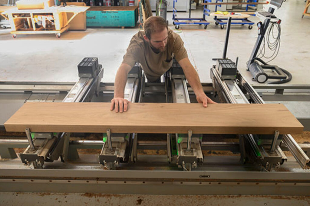 Custom hardwood panel being loaded onto CNC fabrication equipment