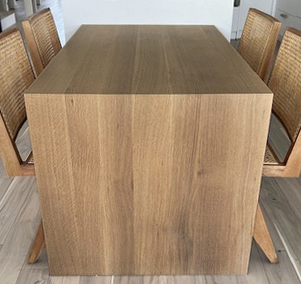 Rift sawn white oak waterfall table showing continuous grain wrapping from the tabletop down the vertical panel