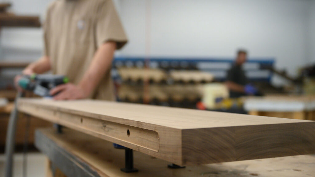 Worker fabricating custom walnut hardwood surface in production shop