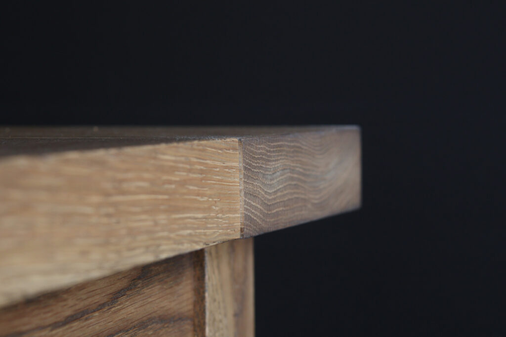 Close-up of a white oak breadboard end detail showing perpendicular grain orientation designed to accommodate natural wood movement